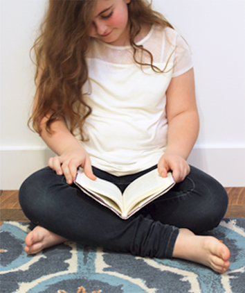 miranda reading a book on a blue leap rug